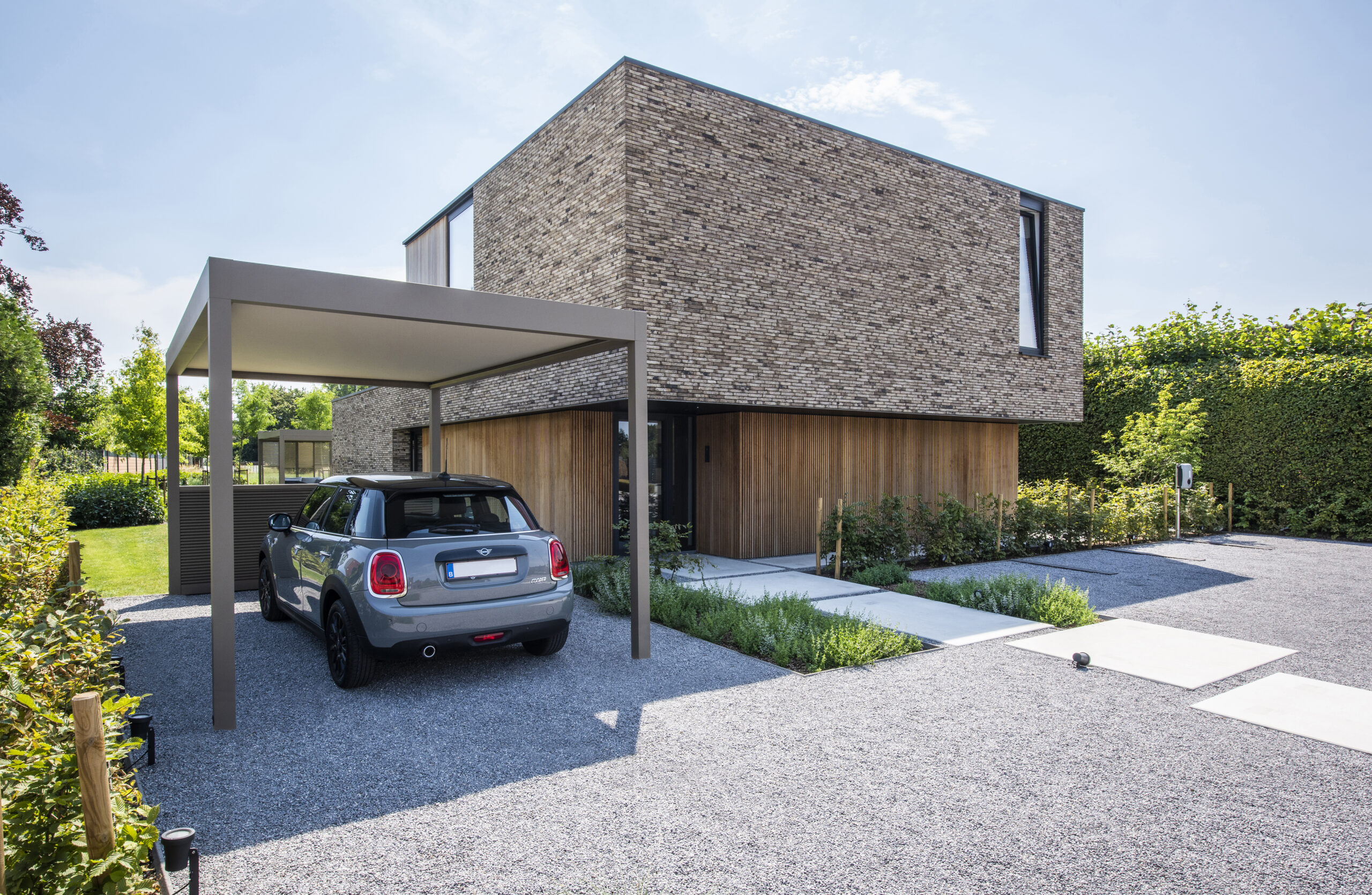 Mini cooper staat onder carport aan de woning